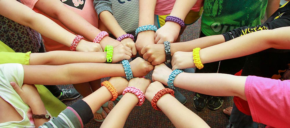 Kids put their fists together in a circle in a show of unity.